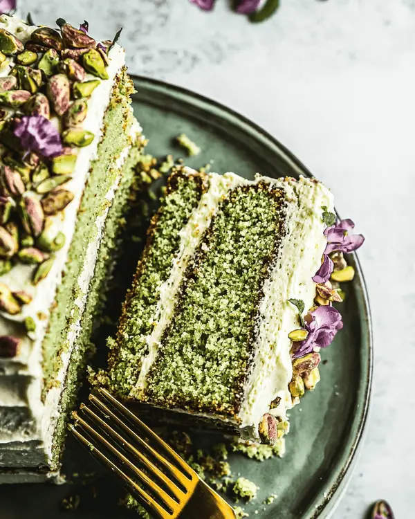 Slices of pistachio butter cake served with pistachio garnish and flowers.